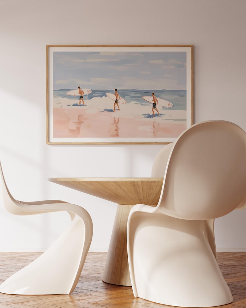 May include: A framed watercolor painting of three people walking on a beach with surfboards. The painting has a light blue sky and pink sand.