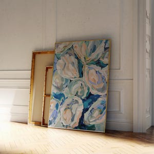 K&ouml;nnte beinhalten: Abstrakte Malerei von gro&szlig;en, wei&szlig;en Blumen mit blauen und gr&uuml;nen Akzenten. Das Gem&auml;lde ist in einem goldenen Rahmen gerahmt und lehnt an einer wei&szlig;en Wand.