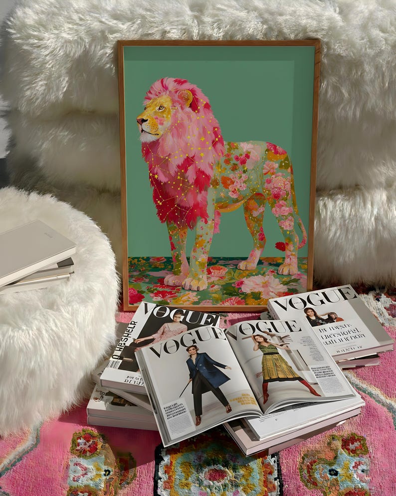 K&ouml;nnte beinhalten: Gerahmter Kunstdruck eines L&ouml;wen mit rosa M&auml;hne und floralem K&ouml;rper. Der L&ouml;we steht auf einer floral gemusterten Oberfl&auml;che vor einem gr&uuml;nen Hintergrund. Vogue-Magazine sind vor dem Druck gestapelt.