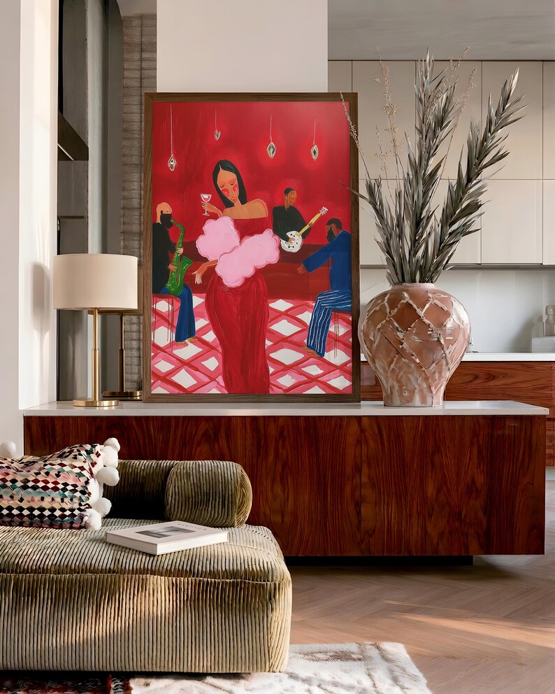 May include: A framed artwork depicts a woman in a red dress with a pink boa, holding a glass of wine, performing in a jazz club. Musicians play saxophone, guitar, and bass. The background is red with hanging lights.