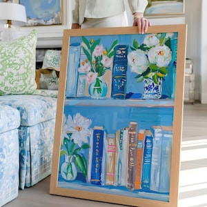 May include: A white ceramic mug with a black handle and the text "But First, Coffee" in a bold, black font. The mug is set against a blurred background, suggesting a cozy setting.