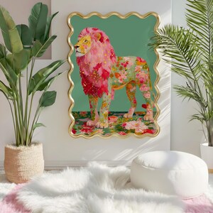 K&ouml;nnte beinhalten: Ein gerahmtes Kunstwerk mit einem L&ouml;wen mit rosa und floraler M&auml;hne und K&ouml;rper. Das Kunstwerk ist vor einem gr&uuml;nen Hintergrund und in Gold gerahmt. Der Raum umfasst Pflanzen, einen wei&szlig;en Teppich und einen wei&szlig;en Ottoman.