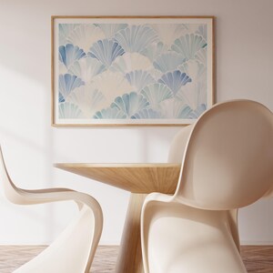 May include: Two white chairs with a wooden table in front of a framed print of a blue and white abstract pattern.