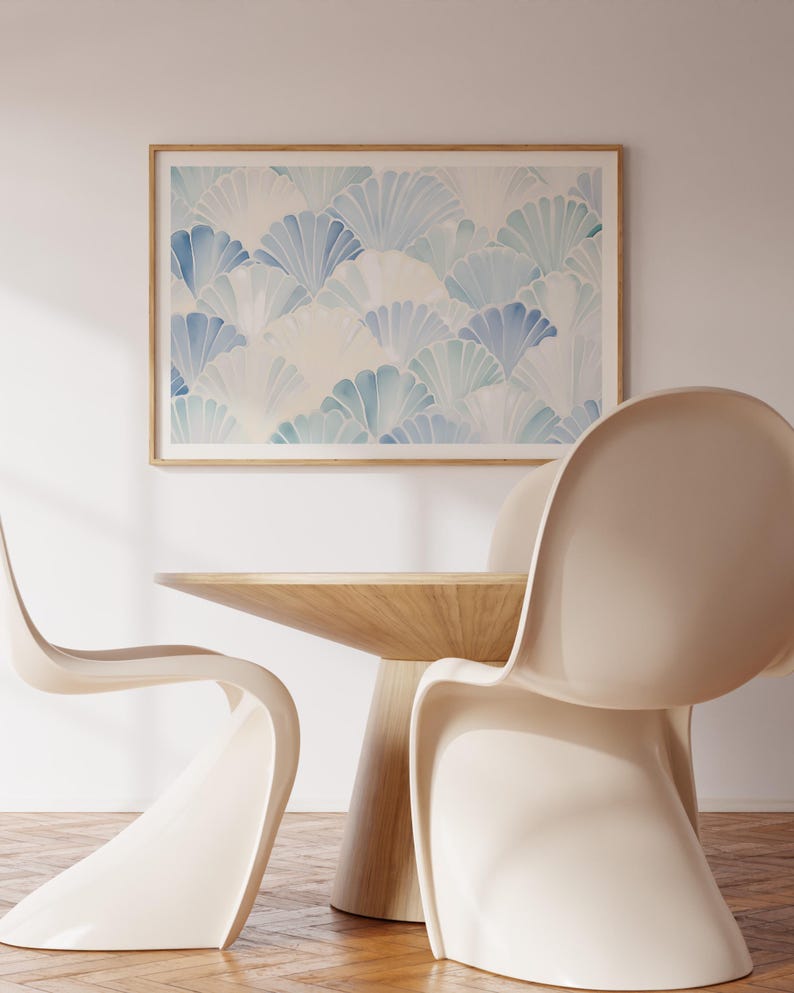 May include: Two white chairs with a wooden table in front of a framed print of a blue and white abstract pattern.