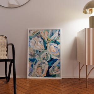 K&ouml;nnte beinhalten: Ein gerahmtes abstraktes Gem&auml;lde mit wei&szlig;en, blauen und gr&uuml;nen floralen Formen auf blauem Hintergrund. Das Gem&auml;lde h&auml;ngt an einer wei&szlig;en Wand in einem Raum mit Holzboden.