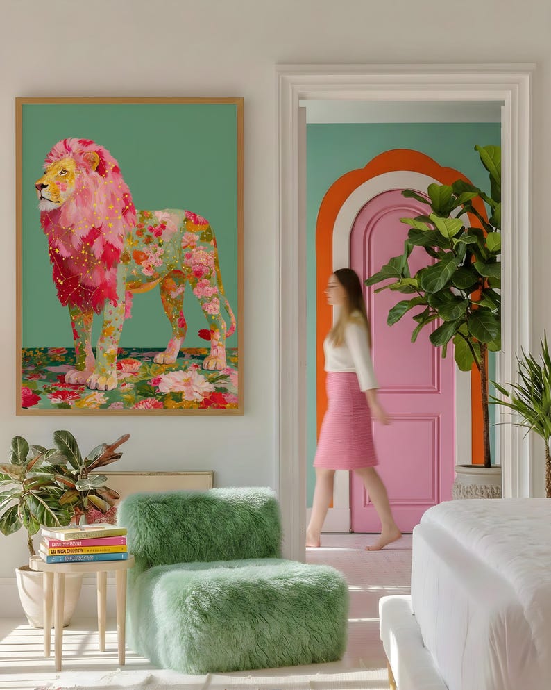 K&ouml;nnte beinhalten: Ein gerahmtes Kunstwerk eines L&ouml;wen mit rosa floraler M&auml;hne und K&ouml;rper, vor einem gr&uuml;nen Hintergrund. Ein gr&uuml;ner, flauschiger Stuhl und ein kleiner Beistelltisch mit B&uuml;chern befinden sich im Vordergrund. Eine Person geht durch eine rosa T&uuml;r.