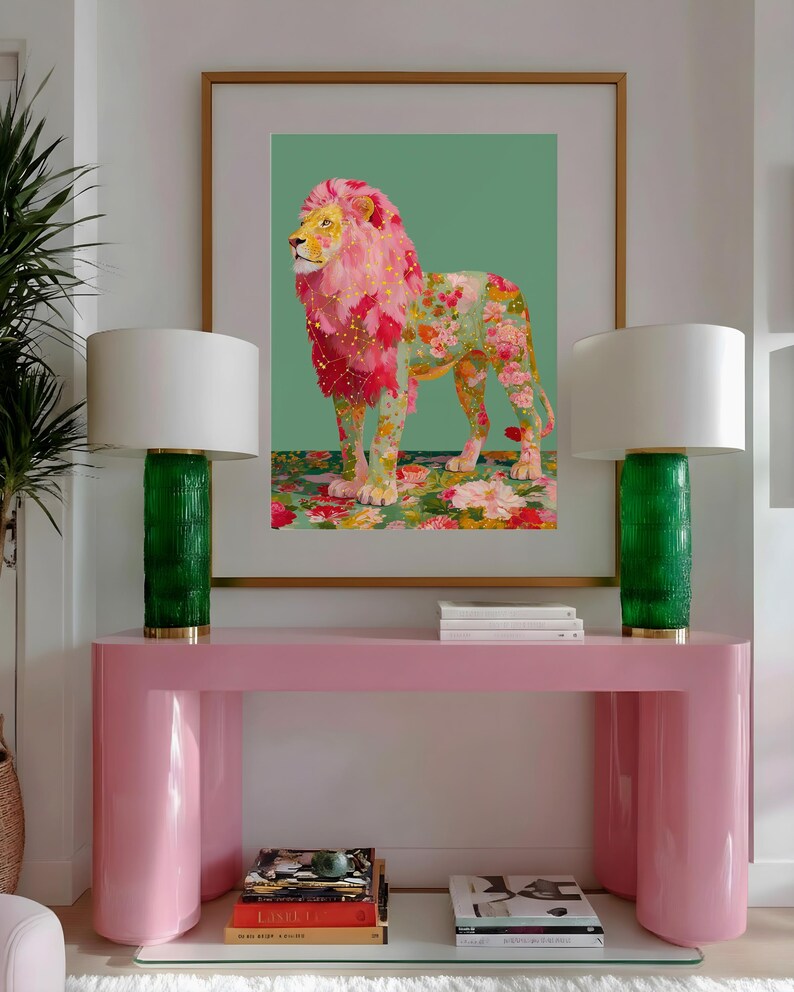 K&ouml;nnte beinhalten: Ein gerahmter Kunstdruck eines L&ouml;wen mit rosa und floraler M&auml;hne und K&ouml;rper, vor einem gr&uuml;nen Hintergrund. Das Kunstwerk wird &uuml;ber einem rosa Konsolentisch mit zwei gr&uuml;nen Lampen mit wei&szlig;en Schirmen ausgestellt. Der Raum hat ein modernes, dekoratives Thema.