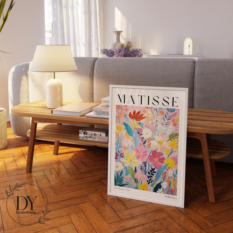 May include: A white framed print with a colorful floral illustration and the text "MATISSE" in bold black letters. The print features a variety of flowers in shades of pink, red, yellow, blue, and green. The text "Vence 1953" and "H. Matisse" are also visible in the bottom right corner.