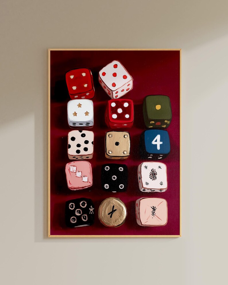 Op de afbeelding: Een ingelijst kunstwerk met een verzameling van twaalf geschilderde dobbelstenen tegen een dieprode achtergrond. De dobbelstenen zijn in verschillende kleuren, waaronder rood, wit, zwart en goud, met verschillende punt- en symboolarrangementen. Het kunstwerk is lichtbruin omlijst.