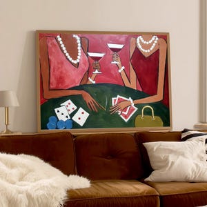 May include: An abstract painting depicts two figures at a poker table, holding wine glasses. The figures wear red and pink dresses and pearl necklaces. Playing cards, poker chips, and a purse are on the green table. The artwork is framed in a wooden frame.