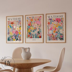 May include: Three framed art prints with a floral design. The prints are in a light wood frame and feature a colorful abstract floral design with pink, yellow, blue, and green flowers. The prints are titled "Matisse" and feature the text "8, Rue de l'Universite, Paris H. Matisse".