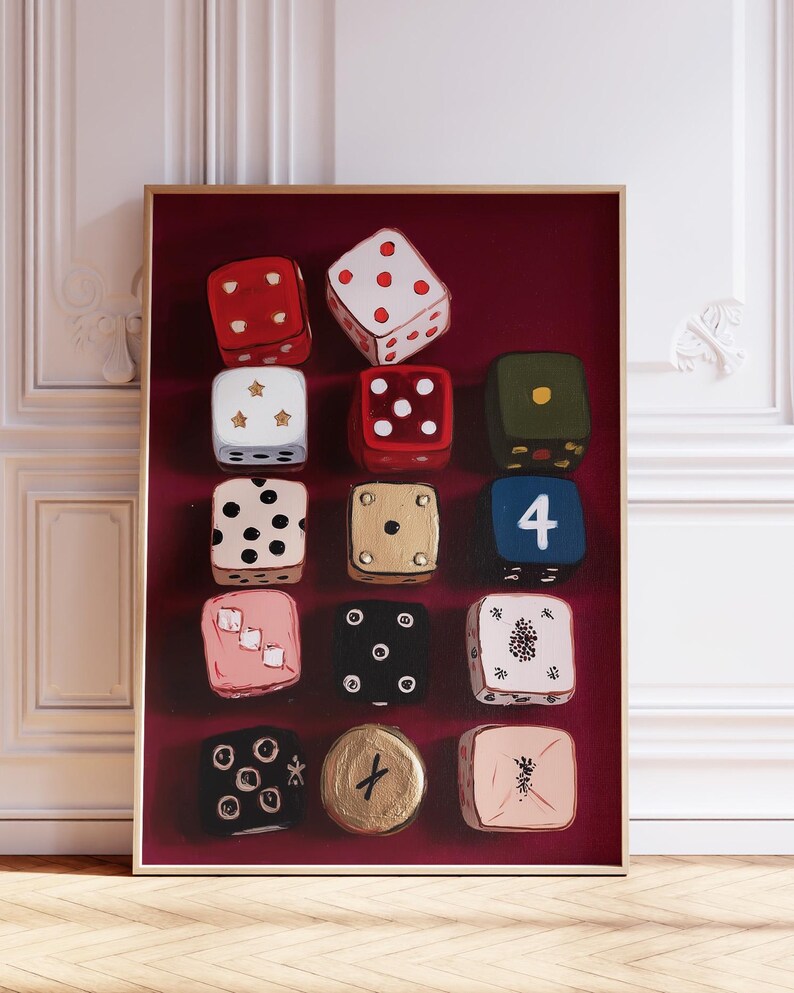 Op de afbeelding: Een ingelijst kunstwerk met twaalf dobbelstenen met verschillende ontwerpen. De dobbelstenen zijn geschilderd in kleuren als rood, wit, zwart, goud en roze, met verschillende punt- en symboolarrangementen. De achtergrond is dieprood.