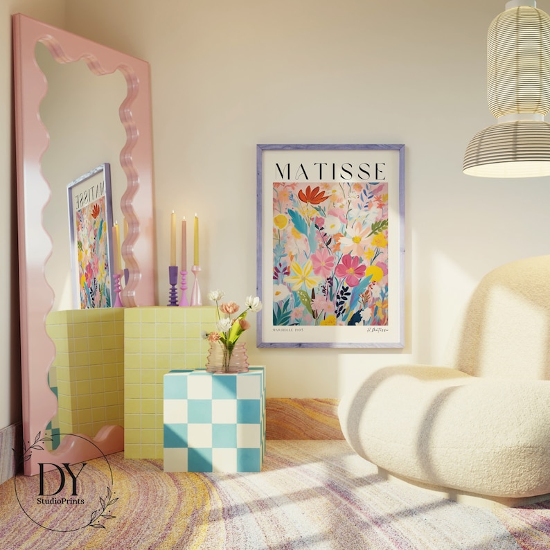 May include: A colorful floral print with the word "MATISSE" in a purple frame, hanging on a light pink wall. The print is surrounded by a yellow tiled shelf, a checkered cube, and a white fluffy armchair.
