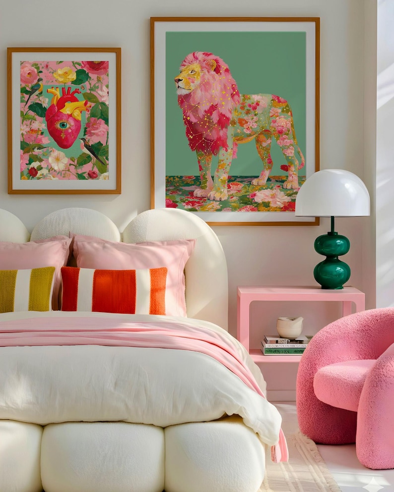 K&ouml;nnte beinhalten: Schlafzimmer-Interieur mit gerahmten Kunstdrucken, einem Bett mit rosa und gestreiften Kissen und einem rosa Nachttisch. Die Kunstwerke umfassen ein Blumenherz und einen L&ouml;wen mit floraler M&auml;hne. Eine gr&uuml;ne Lampe und ein rosa Stuhl vervollst&auml;ndigen die Einrichtung.