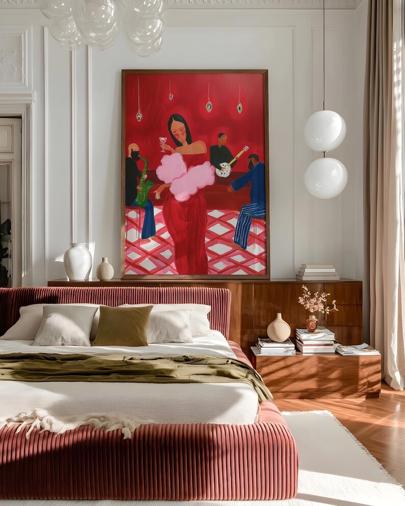 May include: A bedroom featuring a bed with a red-pink, vertically-lined headboard and frame. The bed is made with white linens and an olive green throw. A large painting with a red background and figures at a bar hangs above a wooden dresser.