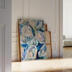 K&ouml;nnte beinhalten: Abstrakte Malerei von blauen, gr&uuml;nen und wei&szlig;en Blumen in einem goldenen Rahmen. Das Gem&auml;lde lehnt an einer wei&szlig;en Wand.