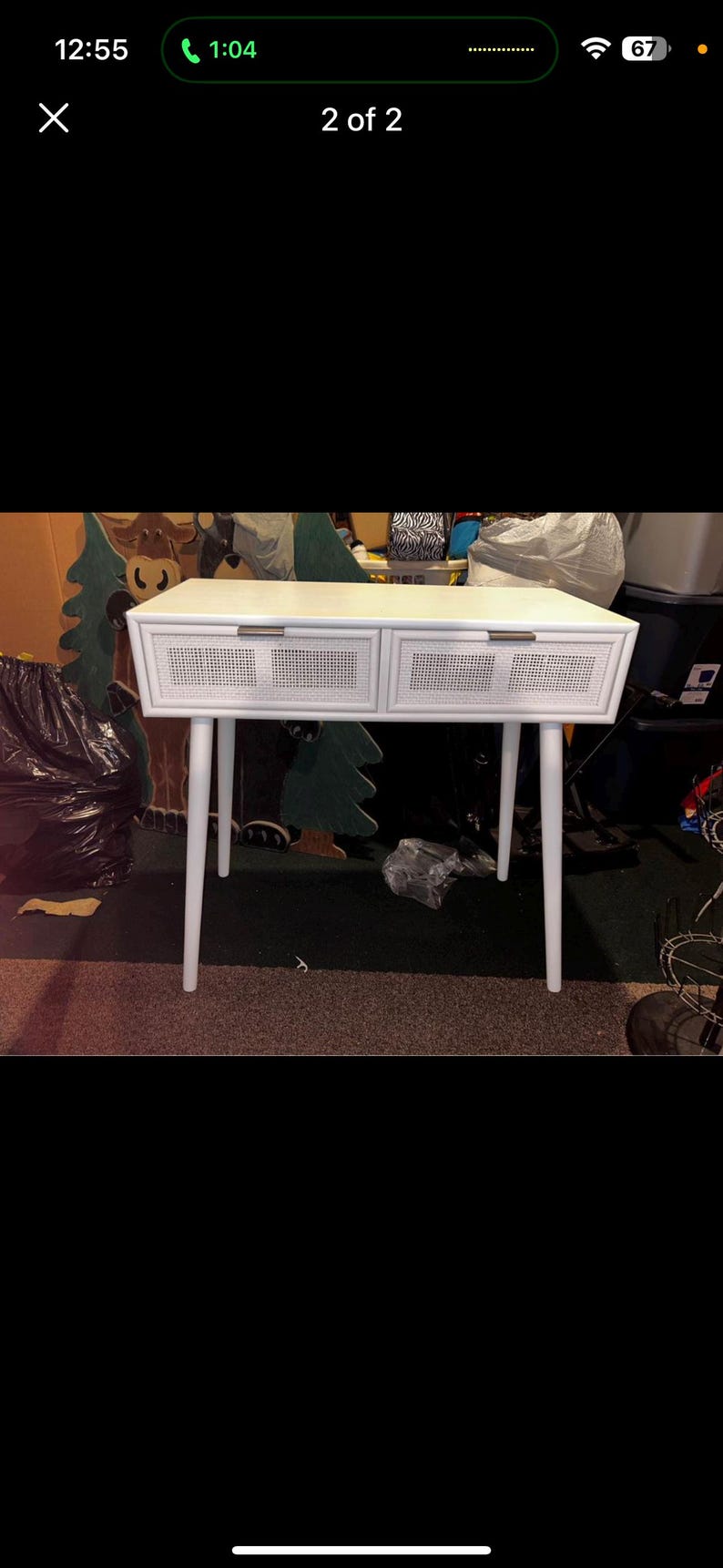 May include: White desk with two drawers and a woven cane design on the drawer fronts. The desk has four white, tapered legs. The desk is a light colour and appears to be made of wood. The desk is a modern style.