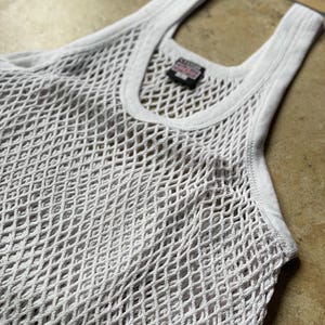 May include: White mesh tank top with a small black label that says "Made in USA".