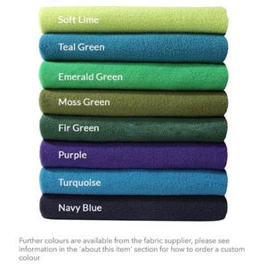 May include: A stack of eight fabric swatches in various shades of green, blue, and purple. The swatches are labeled with the color names: Soft Lime, Teal Green, Emerald Green, Moss Green, Fir Green, Purple, Turquoise, and Navy Blue.