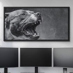 May include: Monochrome framed canvas print of a dog's head, mouth open showing teeth. The artwork hangs above a desk with three computer monitors, a keyboard, and a mouse.