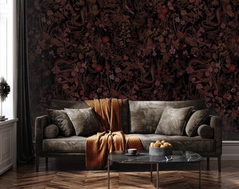 Puede incluir: Un sofá marrón oscuro con una manta y almohadas en una habitación con un papel tapiz floral oscuro. El sofá está delante de una mesa de café con un cuenco de fruta y una taza encima.