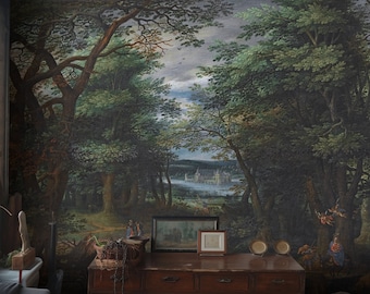 May include: A vintage-style painting of a forest scene with a distant view of a castle. The painting is framed and hanging on a wall above a wooden dresser with drawers. There are two small framed pictures on the dresser, and a few decorative items.