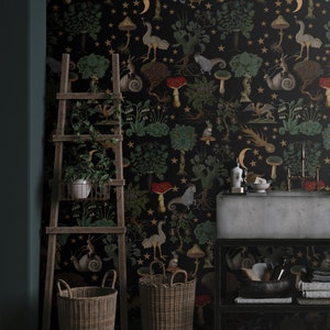 May include: A black and gold wallpaper with a whimsical forest scene featuring mushrooms, stars, and woodland creatures. The wallpaper is displayed in a bathroom setting with a sink, a ladder, and two wicker baskets.