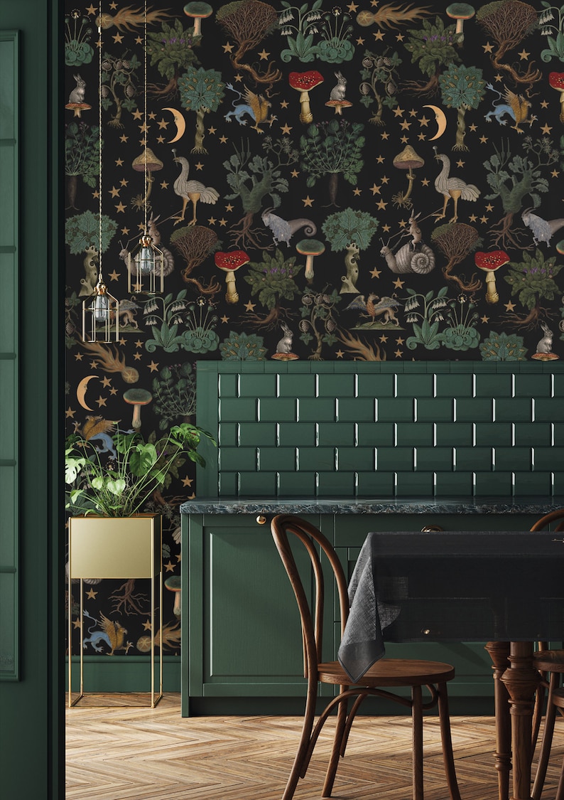 May include: A dark green kitchen with a black and gold wallpaper featuring a whimsical forest scene with mushrooms, stars, and mythical creatures. The wallpaper is on the wall behind a green tiled backsplash and a dark green cabinet. There are two wooden chairs with black cushions and a black tablecloth on the table.