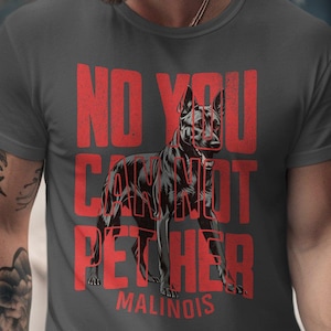 May include: A charcoal gray t-shirt with the text "NO YOU CAN'T PET HER" in red, along with a graphic of a Malinois dog. The word "MALINOIS" is printed in red below the dog graphic.