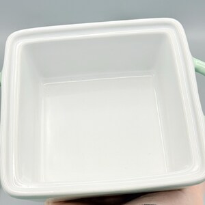 Puede incluir: Una fuente para hornear cuadrada de cer&aacute;mica blanca con esquinas redondeadas y un asa verde claro a cada lado. El interior es brillante y vac&iacute;o. La fuente est&aacute; dise&ntilde;ada para hornear y servir.