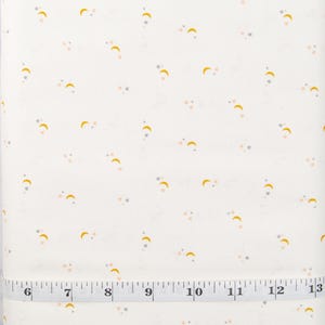 May include: White fabric with a repeating pattern of small yellow crescent moons, pink stars, and gray stars. A ruler is visible at the bottom of the image with the text "PRETTY CUTE QUILTS".