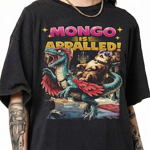 May include: A white ceramic mug with a black handle and the text "But First, Coffee" in a black, handwritten-style font. The mug is on a white surface.