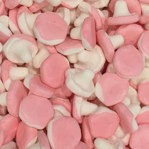 Puede incluir: Primer plano de un montón de caramelos con forma de hongo. Los caramelos son una mezcla de rosa y blanco, con el rosa formando la tapa y el blanco el tallo. Un dulce colorido y dulce.