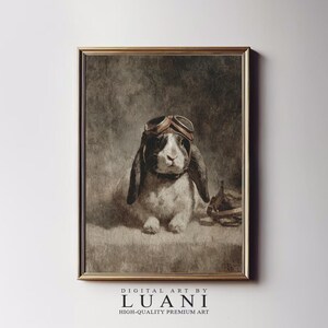 May include: Framed vintage-style print featuring a rabbit wearing aviator goggles. The rabbit has black and white fur and long ears. The print has a sepia tone and is framed in a gold-colored frame. The text "DIGITAL ART BY LUANI HIGH-QUALITY PREMIUM ART" is at the bottom.
