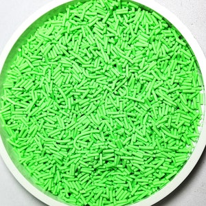 Peut inclure: Un bol blanc rempli de vermicelles de couleur vert vif. Les vermicelles sont longs et fins, ressemblant à de petits bâtonnets.