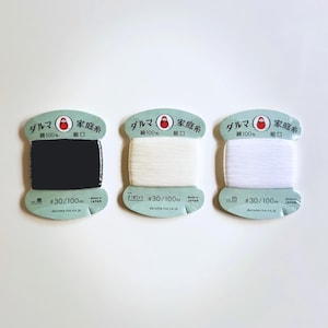 May include: Three spools of Daruma brand cotton thread, each wrapped on a card with a red daruma logo. The threads are black, off-white, and white. Each card is labeled with #30/100m, 100% cotton, and Made in Japan, featuring Japanese text.