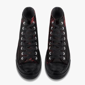 May include: Pair of high-top trainers in black with a red splatter design. The trainers have black laces, a black rubber toe cap, and a black sole. The eyelets are silver.