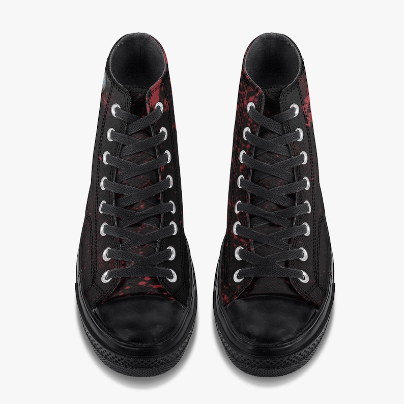May include: Pair of high-top trainers in black with a red splatter design. The trainers have black laces, a black rubber toe cap, and a black sole. The eyelets are silver.