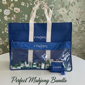 May include: A navy blue canvas tote bag with cream handles, a matching clear-front zippered pouch, and a small navy coin purse. Each item features the word Mahjong in white script. Green and white mahjong tiles are visible inside the clear pouch.