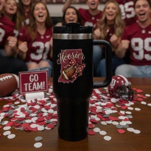 May include: A black travel mug with a handle, featuring a "Hoosier" graphic with a football and a bow. The mug is surrounded by red, white, and gray confetti, a football, and a sign that says "GO TEAM!"