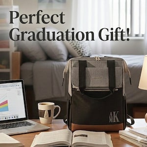 May include: A gray, black, and brown backpack with the text "Perfect Graduation Gift!" is displayed on a wooden desk. The backpack has a monogram with the letters "AK". A laptop, coffee mug, and open book are also on the desk.