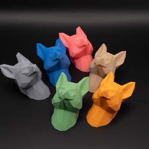 Könnte beinhalten: Sieben geometrische Tierschädel-Skulpturen in verschiedenen Farben, darunter Grau, Blau, Grün, Orange, Braun und Pink. Die Skulpturen sind aus einem glatten, matten Material gefertigt und haben ein modernes, minimalistisches Design.