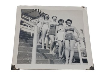 Vintage-Foto einer Gruppe von Frauen aus den 1950er Jahren, die in zweiteiligen Badeanzügen auf Treppen posieren