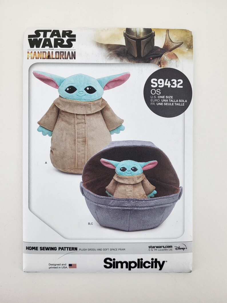 K&ouml;nnte beinhalten: Ein Schnittmuster f&uuml;r einen Pl&uuml;sch-Grogu und einen weichen Weltraumkinderwagen. Das Muster zeigt Bilder des Grogu-Pl&uuml;schtiers, eines stehend und eines in einem Kinderwagen. Das Star Wars Mandalorian-Logo befindet sich oben, das Simplicity-Logo unten.