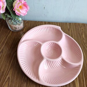 Könnte beinhalten: Eine rosa Keramik-Servierplatte mit vier Abschnitten. Die Platte hat ein Spiraldesign und ist perfekt zum Servieren von Snacks oder Vorspeisen.