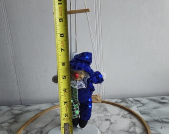ブランコに乗ったヴィンテージの磁器製ピエロ人形。緑と青の布が