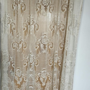 Peut inclure: Rideau en dentelle blanche avec un motif floral délicat. Le rideau est transparent et a un ourlet festonné.