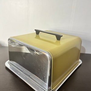 Peut inclure: Un dôme à gâteau jaune et argent avec une poignée noire. Le dôme est en métal et a une finition brillante. La poignée est fixée au sommet du dôme et est en plastique.