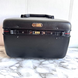 May include: Black hard-sided carry-on suitcase with a combination lock and the text "SIDIVA" in gold lettering.