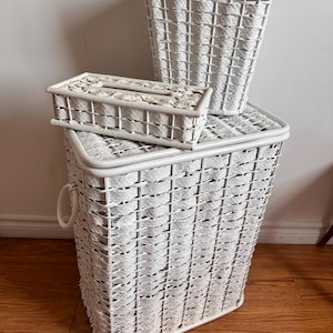 May include: Three white wicker baskets, one tall and rectangular, one square, and one smaller rectangular. The baskets are woven with a white material and have a natural, rustic look.